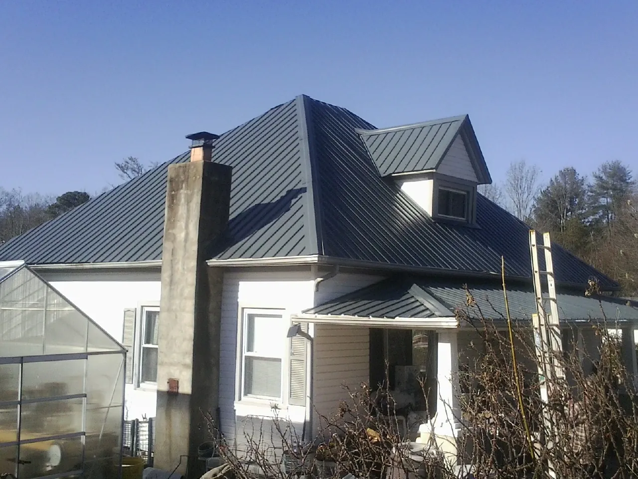 Dark blue standing seam metal roof on a white farmhouse with dormer — Slate & Tile Roof Repair by Roofing Brothers in Dresher