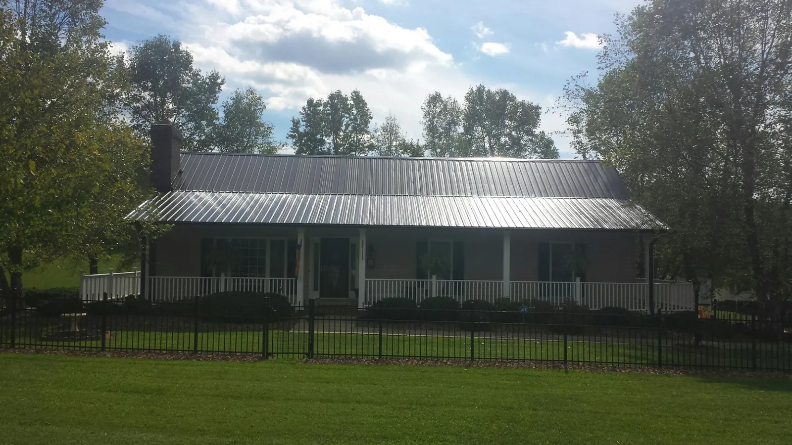 Gray metal roof on a brick ranch with a full width front porch — Gutter Guard Installation work by our crew in Dresher