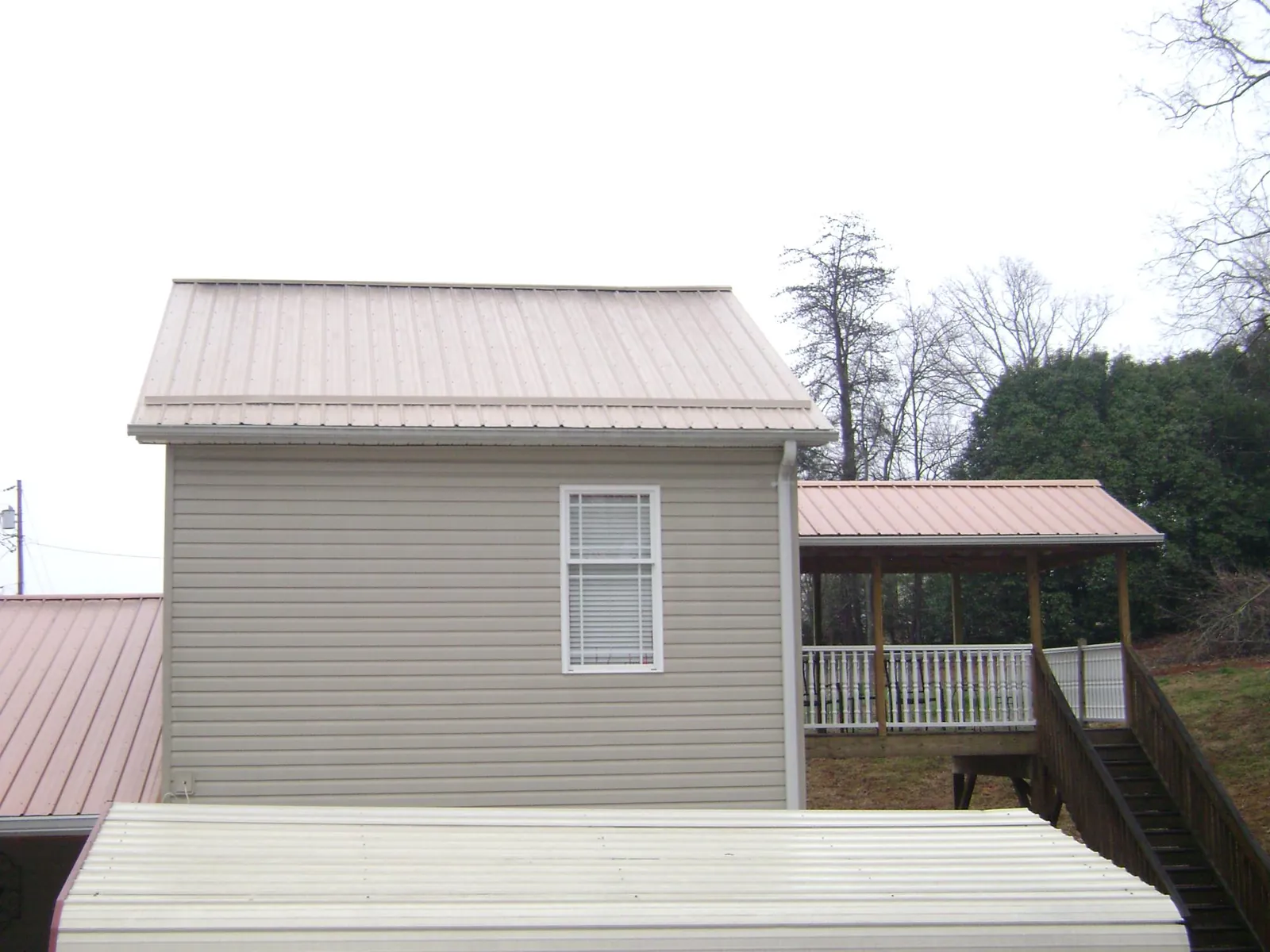 Tan metal roofs on a two story addition and attached porch, from a Roof Replacement job in Dresher