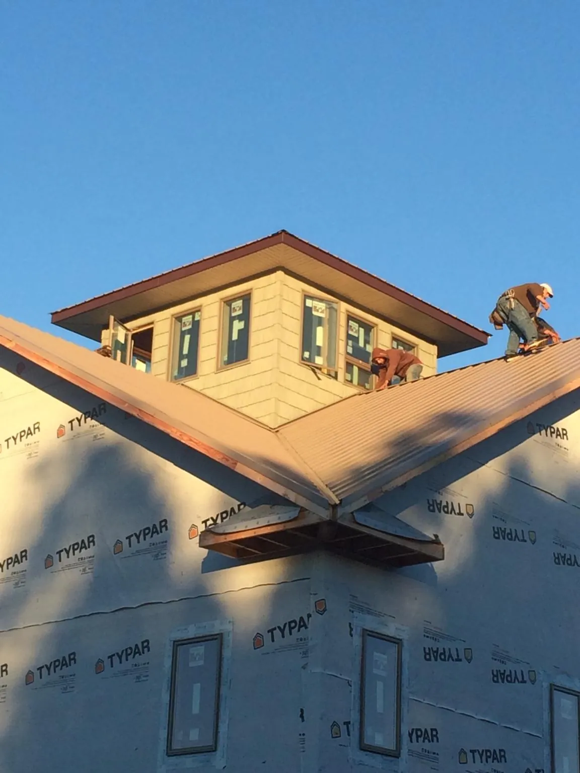 Roofers working around a rooftop cupola on a new metal roof at sunset — Roof Waterproofing in Dresher by Roofing Brothers